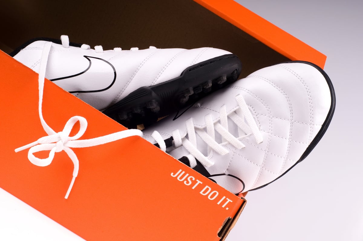 Black and white Nike indoor soccer shoes in orange packaging